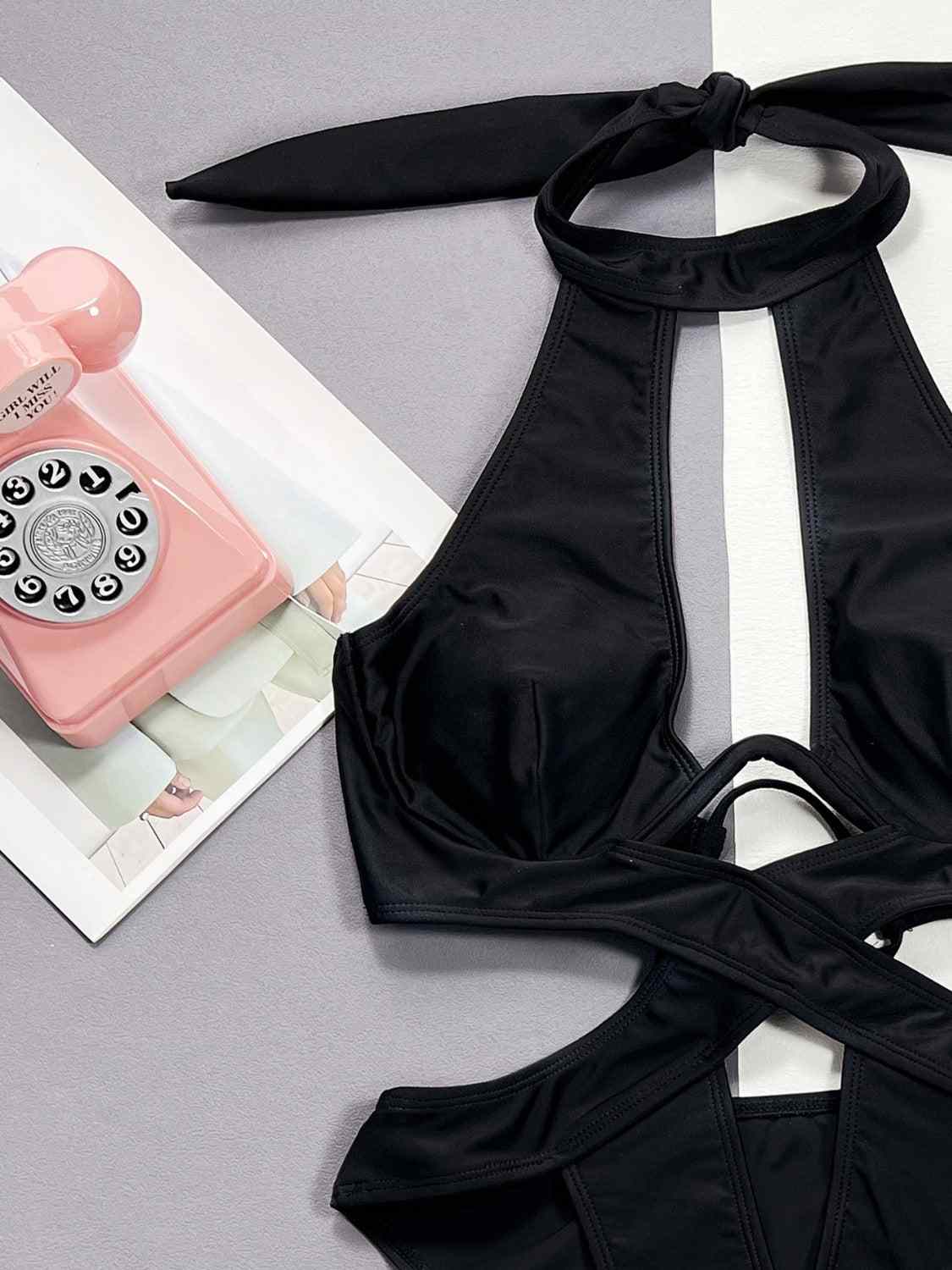 Cutout halter neck one-piece swimwear with removable padding and underwire, made of nylon and spandex.