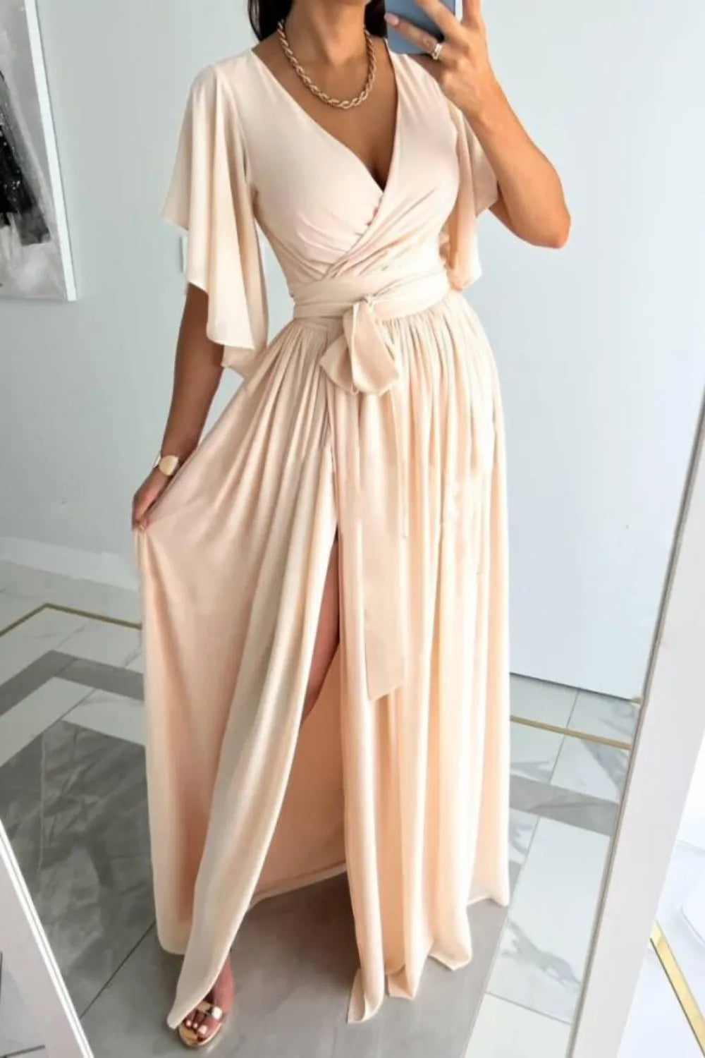 Surplice flutter sleeve maxi dress with tied waist and slit, made of polyester and spandex.