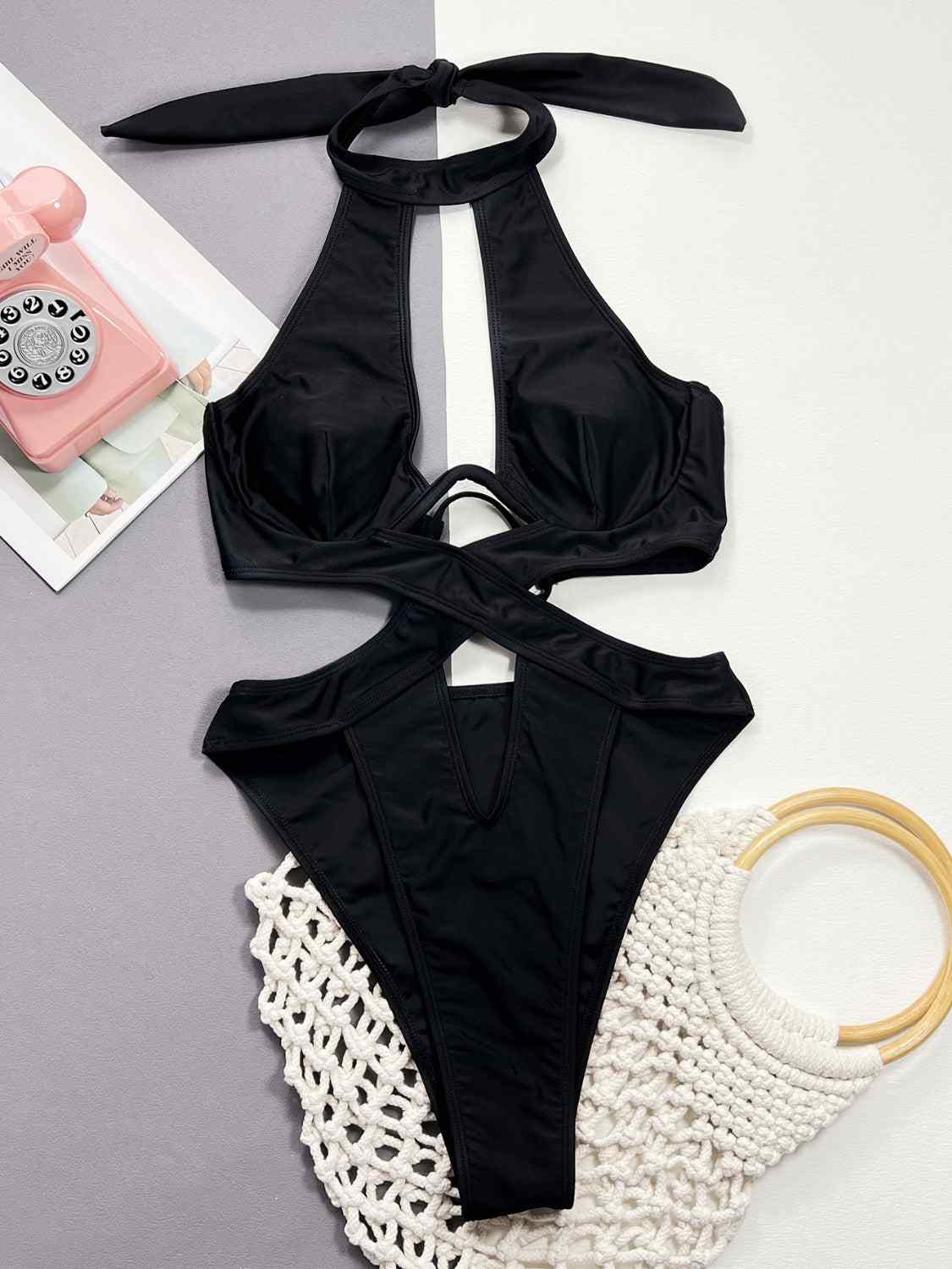 Cutout halter neck one-piece swimwear with removable padding and underwire, made of stretchy nylon and spandex.