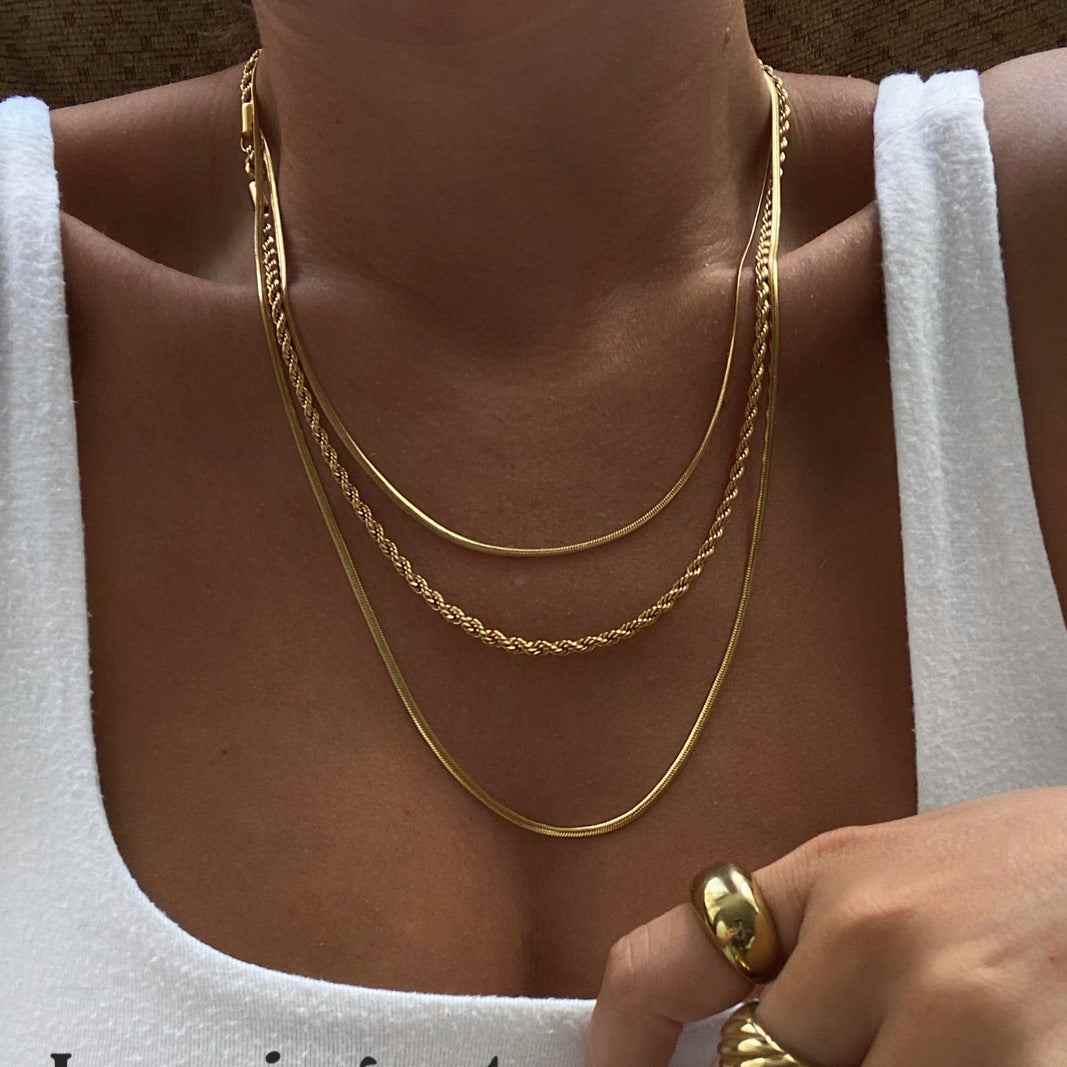 18K gold-plated titanium steel three-layered necklace displayed on a woman wearing a white top.