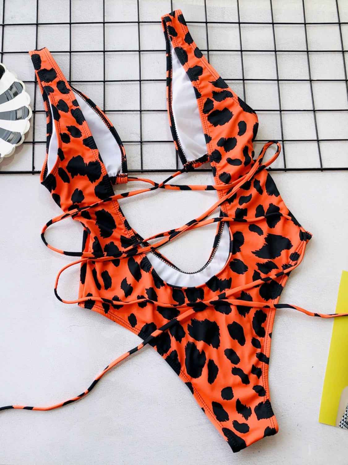 Lace-up backless plunge one-piece swimwear with orange and black leopard print design.