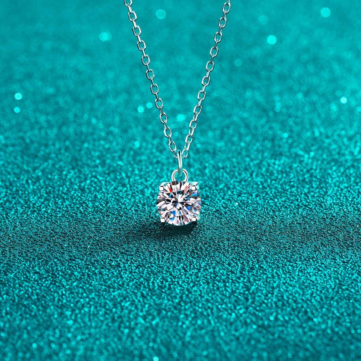 1 carat moissanite necklace in 925 sterling silver on teal background.